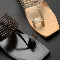 Close-up of a black sandal and a beige sandal on a dark background
