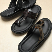 Pair of black sandals with brown straps on a beige background