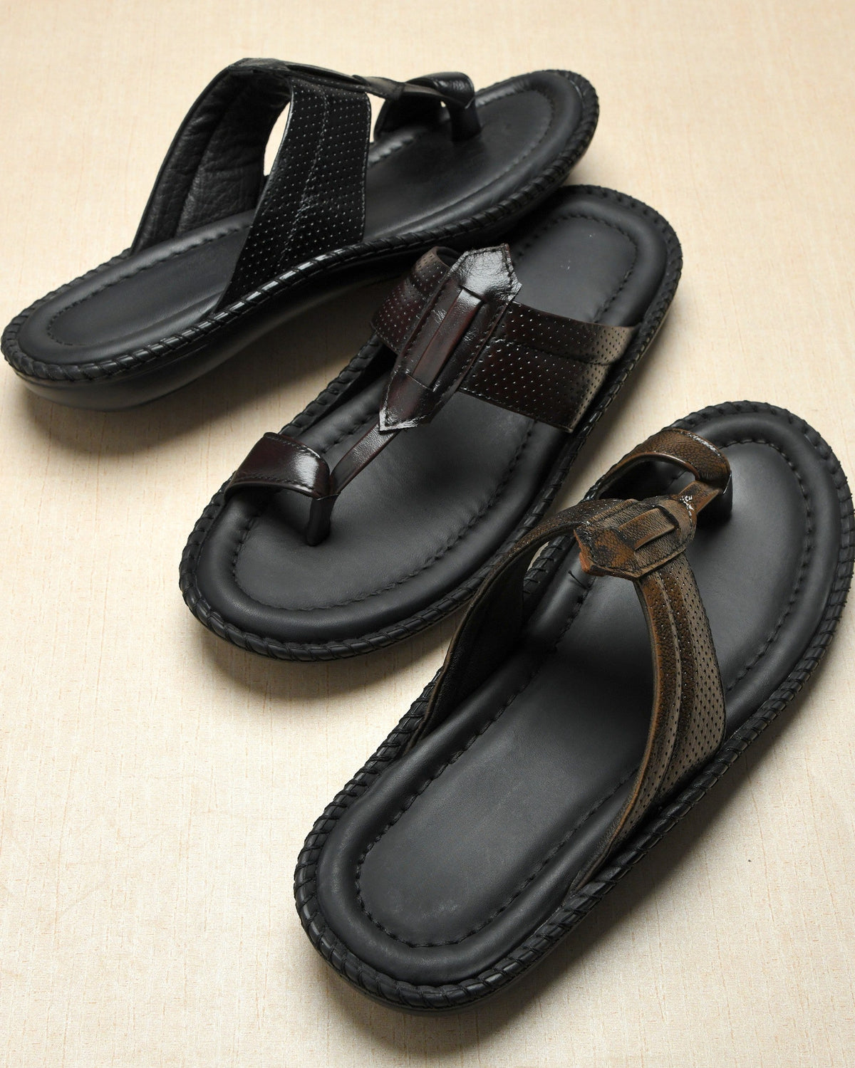 Pair of black sandals with brown straps on a beige background