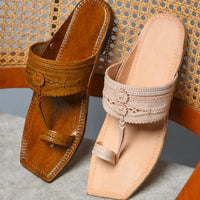 Pair of brown and beige sandals on a textured surface with wicker chair background